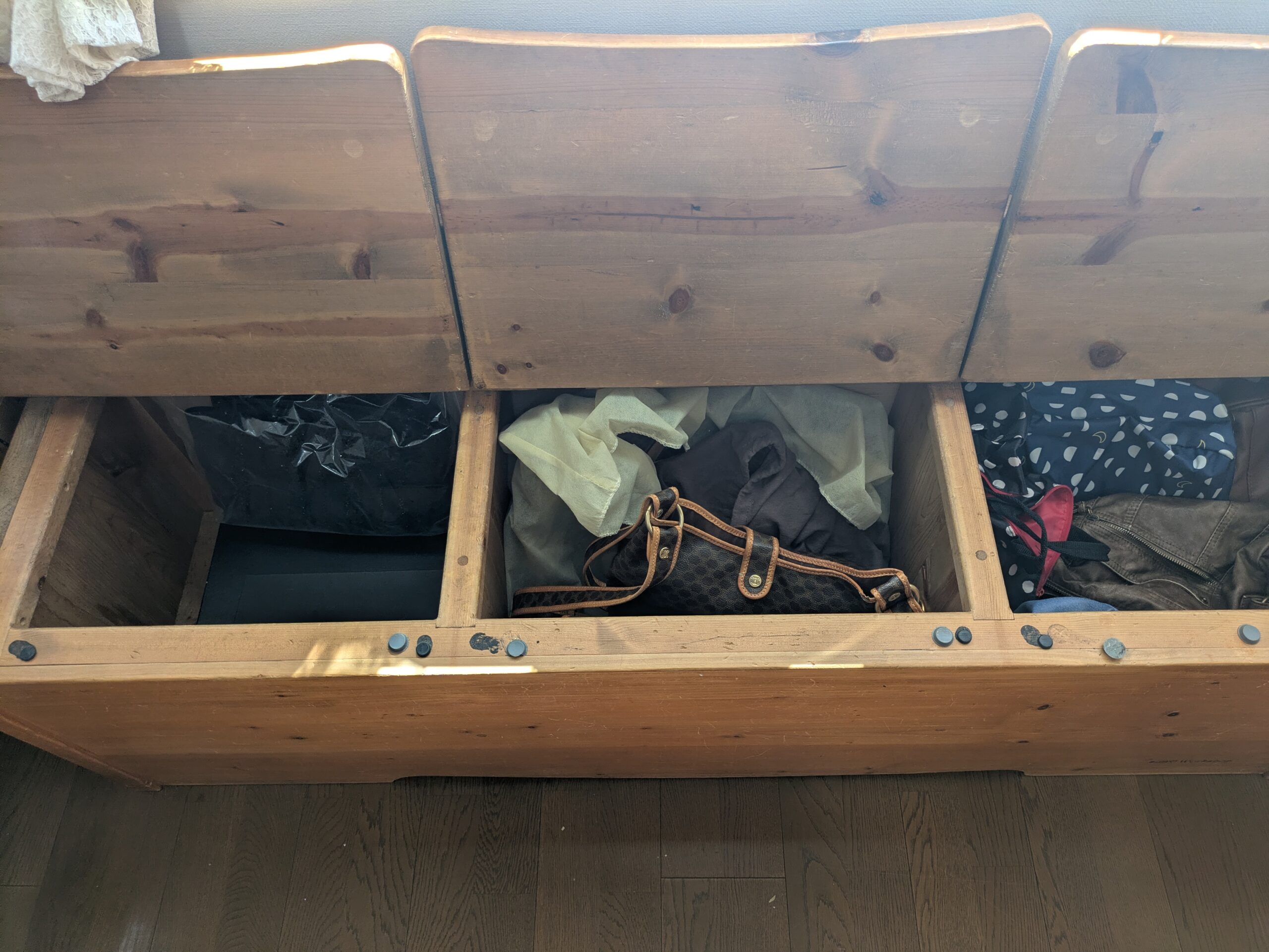 ふたを開けた木製収納ベンチと、中に保管しているバッグ